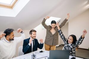 Diverse group of professionals celebrate a team success in a contemporary office setting.